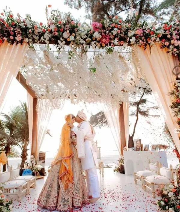 A breathtaking beachside mandap for a destination wedding in Goa, where the couple exchanges vows under a canopy of lush florals with the Arabian Sea as their witness. This is the epitome of a romantic, luxury wedding ceremony.