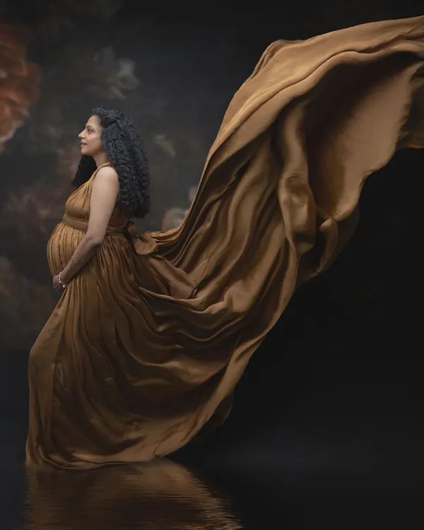 The golden glow of motherhood. The rich, warm tones of this maternity gown reflect the nurturing energy of this journey, with the dramatic sweep of fabric giving the impression of life in motion.