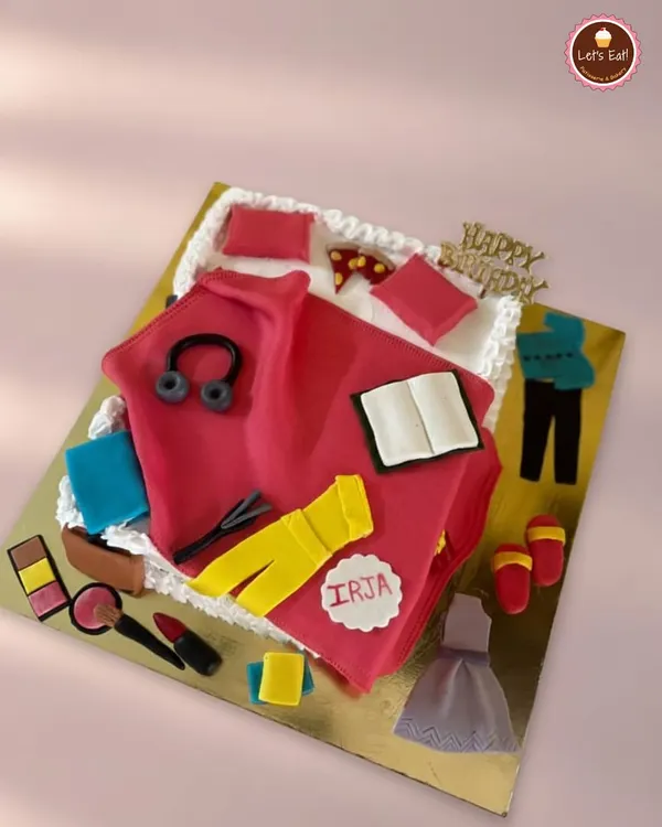 This cake was designed for someone with many passions. It features edible fondant creations representing makeup, books, music, and fashion, all arranged on a cake shaped like a folded shirt. It’s a great example of a truly personalized design.