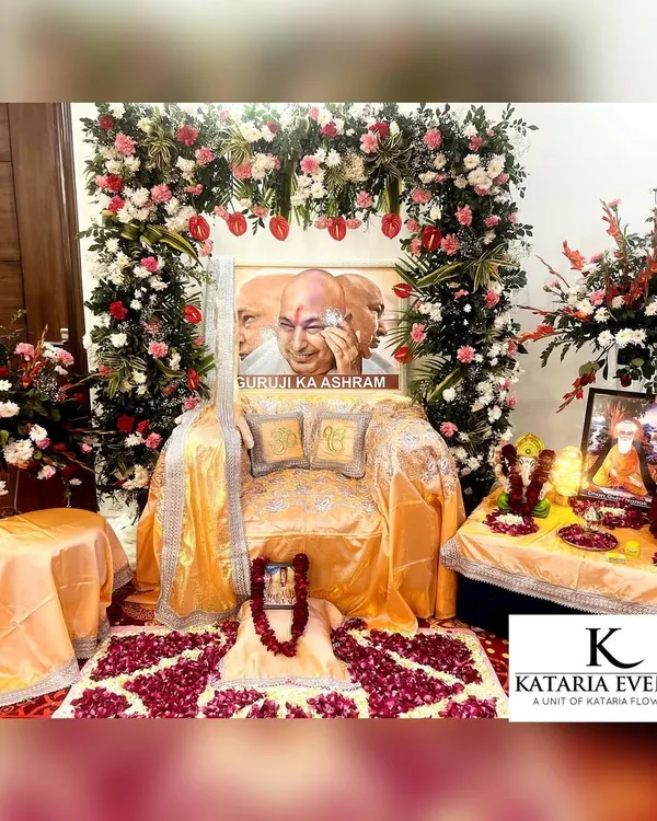 A complete Satsang decor setup I created, featuring a floral arch with red and pink roses over Guru ji's aasan. The seating is draped in golden fabric, and the floor is decorated with a rose petal rangoli to create a blessed space.