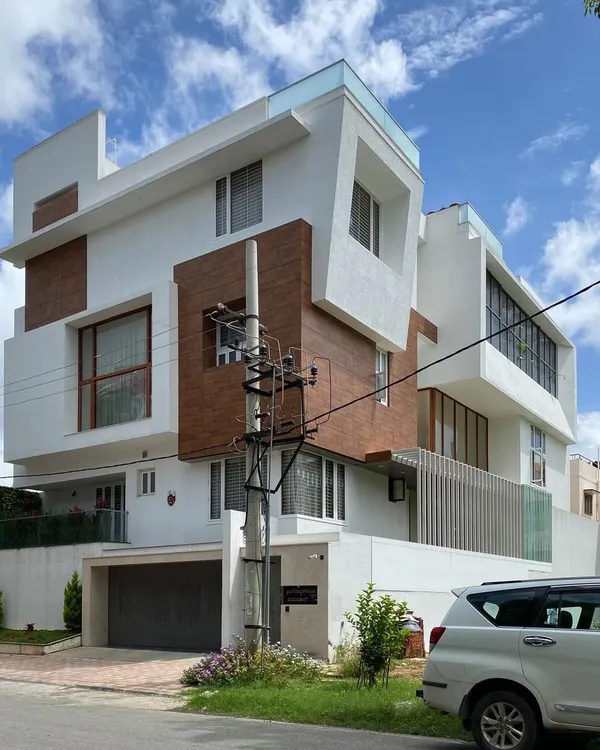 A contemporary residence for Mr. Satish, defined by its interlocking blocks, cantilevered structures, and a mix of wood-paneled and white stucco surfaces.