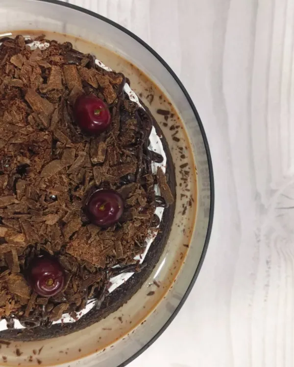An aerial view of my Black Forest Tres Leches cake. This shows the rich chocolate shavings and fresh cherries that top the moist, chocolate-soaked sponge, promising a decadent experience.