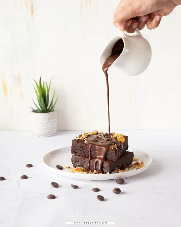 This shot is all about capturing a moment of pure indulgence. I used a fast shutter speed to freeze the motion of the rich chocolate sauce as it cascades over the brownie, creating a dynamic and delicious scene. The bright, clean lighting makes the texture of the brownie and the gloss of the sauce pop.