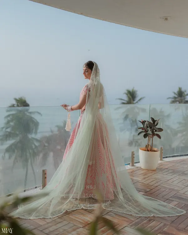 A breathtaking shot of the bride on a balcony overlooking the ocean, her long veil flowing in the breeze. A truly cinematic bridal portrait.