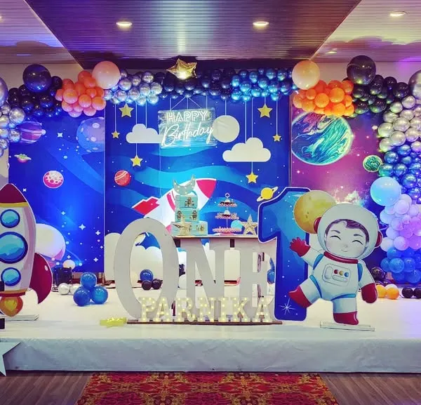 This outer space themed first birthday is one of my favorites. The full stage setup includes a galaxy backdrop, planet and star cutouts, a custom rocket ship, and marquee letters spelling 'ONE' for the perfect photo opportunity.