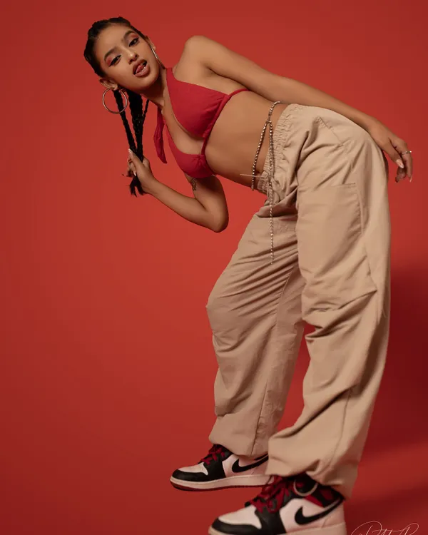 A dynamic pose against a bold red background. This shot captures the urban and edgy side of my style, blending dance and fashion.