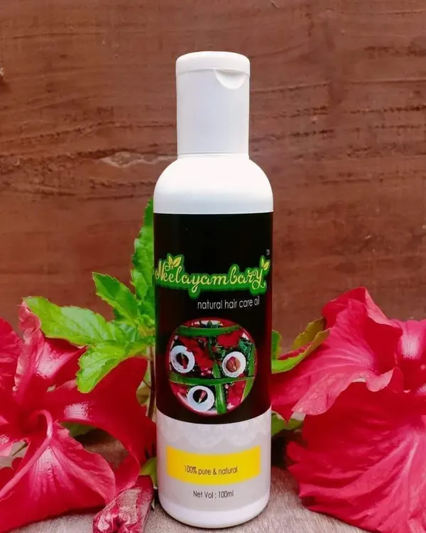 A bottle of my Natural Hair Care Oil, surrounded by fresh hibiscus flowers. This oil is 100% pure and natural, made to solve problems like hair fall and premature greying, and to give you healthy, nourished hair.