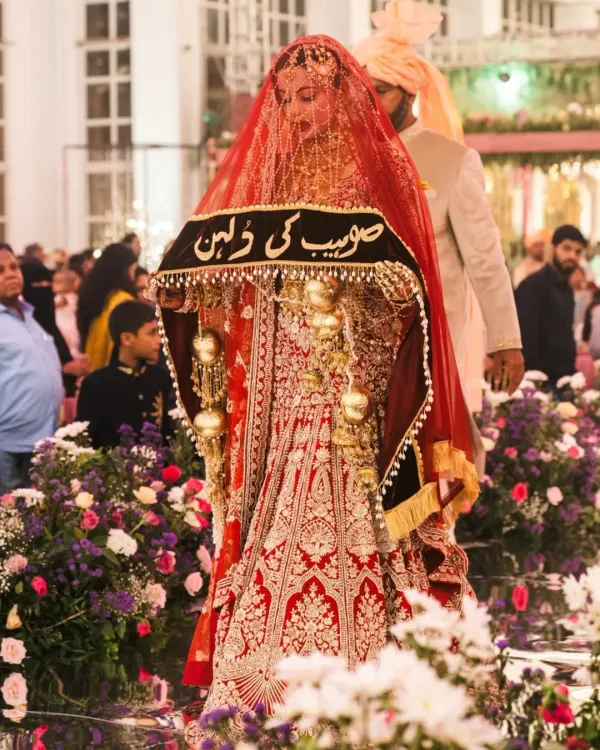 Veiled in majesty, this bride shines in an eternal red lehenga for her Nikah. The personalized veil adds a layer of heritage, making her entrance truly unforgettable.