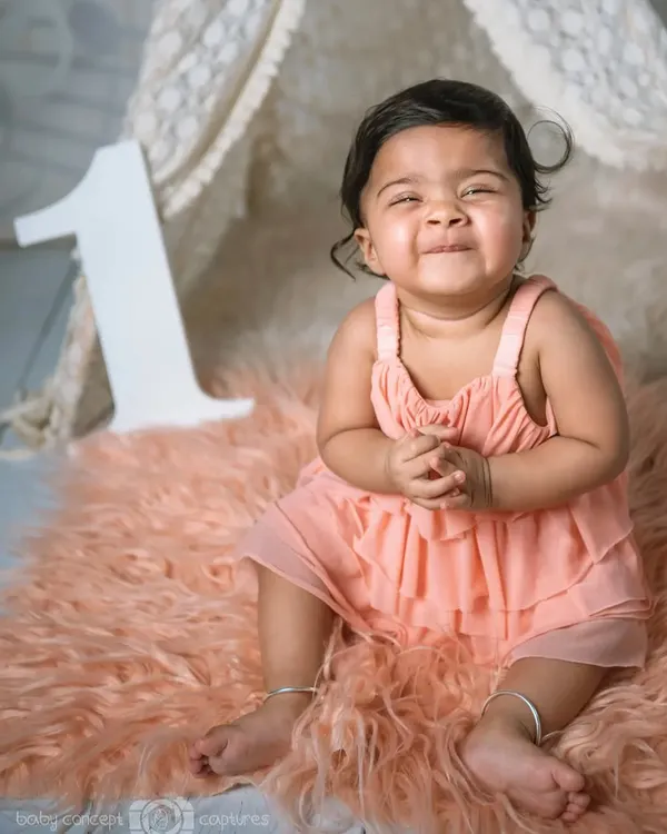 That proud "I'm turning one!" smile. This photo captures the excitement of a baby reaching their first birthday milestone, even before the cake comes out.