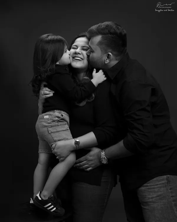 A huddle of love. This black and white family portrait is overflowing with kisses and joy, a perfect freeze-frame of happiness.