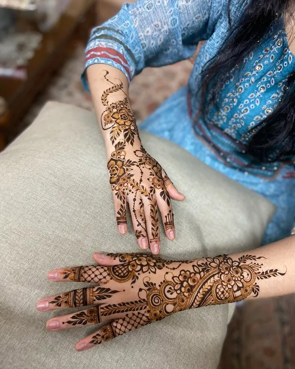 This design shows a beautiful contrast. One hand has a dense, Indian-style pattern, while the other features a flowing Arabic vine, or 'bel'.