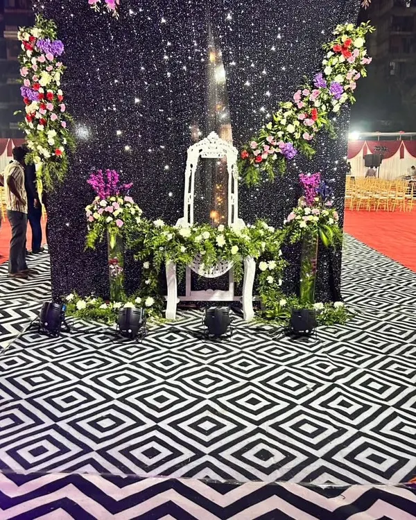 A unique photo prop featuring a traditional mirror stand decorated with floral arrangements. This was set against a sparkling black backdrop, creating a glamorous and interactive spot for guests to take pictures.