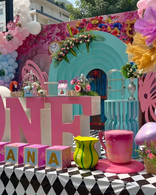 This vibrant 'Ahana's Onederland' setup was so much fun to create. I used a bold pink and turquoise color palette, a checkerboard floor, and oversized props like the 'ONE' letters and a giant teacup to capture the whimsical spirit of Wonderland.