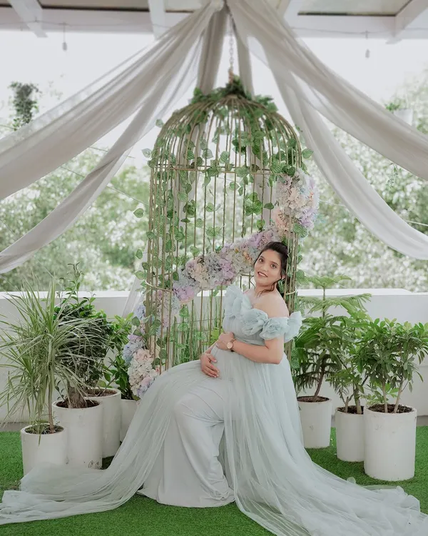 A serene and angelic portrait of an expecting mother in our light blue 'Isabella' gown. The off-shoulder design and flowing tulle create a soft, ethereal look, perfect for a maternity photoshoot.