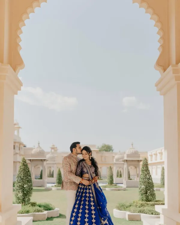 A quiet moment of affection at The Oberoi Udaivilas. The groom's gentle kiss on her forehead is framed by the palace's iconic arches, a perfect blend of regal architecture and intimate emotion for this Udaipur pre-wedding shoot.