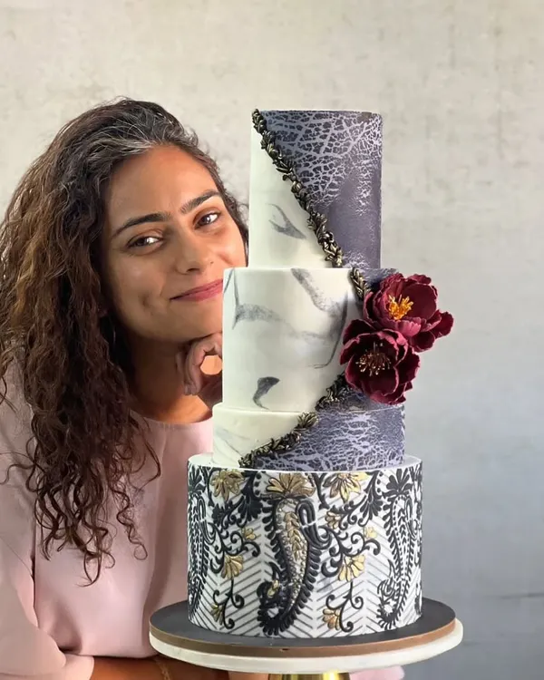 This is me with one of my proudest creations, a three-tiered wedding cake. I love pushing my creative boundaries with advanced techniques like marbled fondant and intricate patterns to make your big day truly magical.