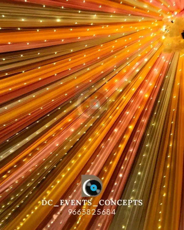 A mesmerizing ceiling treatment using colorful drapes and interwoven fairy lights, creating a vibrant canopy that radiates outwards from the center.