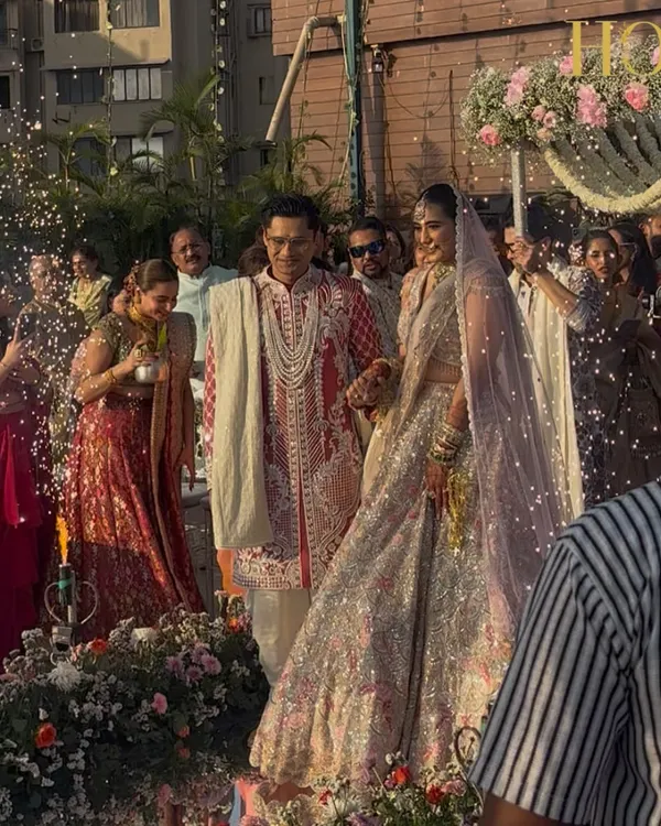 The bride and groom's grand entrance at their seaside wedding, with a beautiful floral mandap and the ocean creating a stunning natural backdrop.
