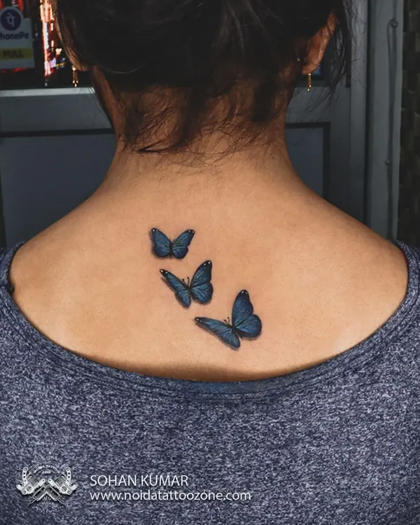 These three-dimensional blue butterflies look like they could fly right off the skin. We use careful shading and color blending to create a realistic and delicate effect for this back tattoo.