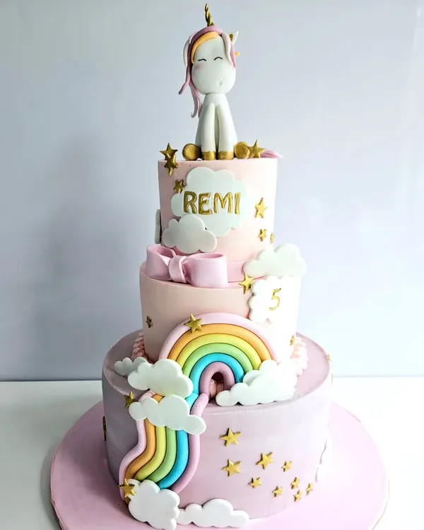 This three-tier unicorn cake is a dream come true for any magical party. It features soft pastel pink frosting, a cascading rainbow, fluffy clouds, and a cute unicorn topper, all made to create a whimsical birthday celebration.