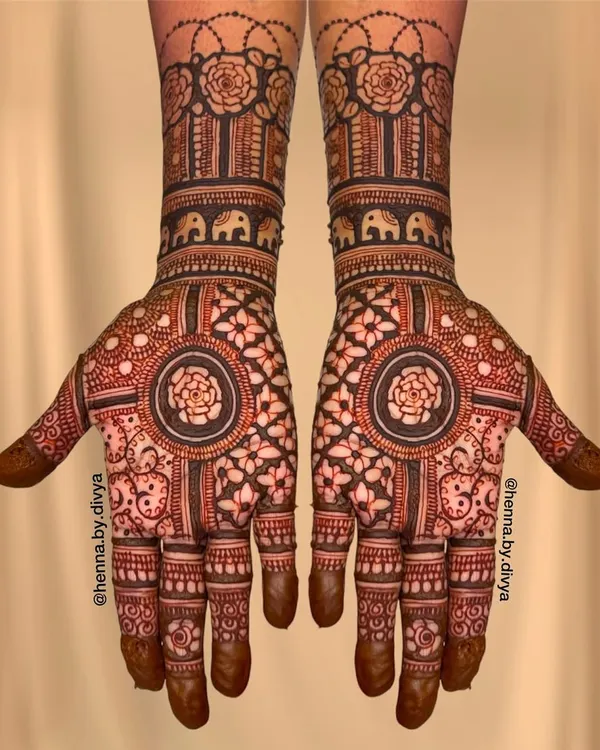 A beautiful Indian mehendi design with a central floral mandala. The wrists are adorned with bands of roses and elephants, blending different traditional elements.