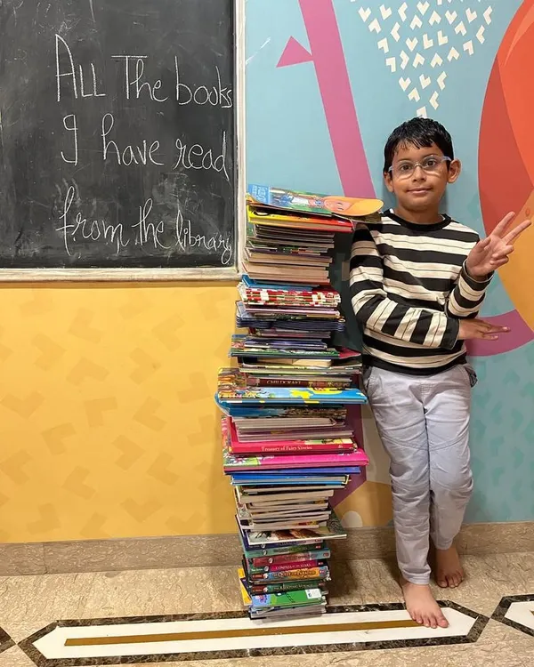 Another one of our avid readers standing proudly next to the tower of books he has read from our library. We celebrate every reading milestone.