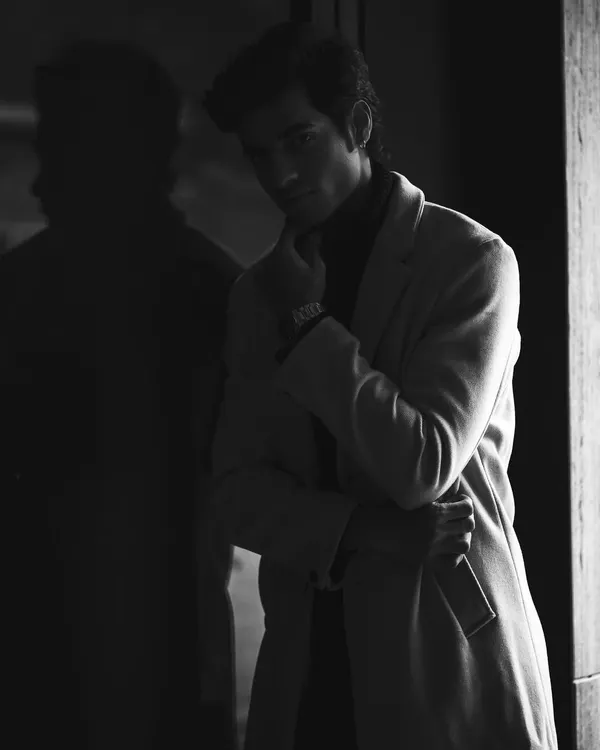 A dramatic black and white portrait where the model is partially obscured by shadow, creating a sense of mystery and intrigue. This is a powerful editorial style.