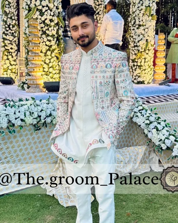 A modern groom looking sharp in our three-piece Rajwada shrug set. This Indo-Western outfit features intricate, multi-colored threadwork on an ivory base, perfect for making a statement at a day wedding or sangeet.