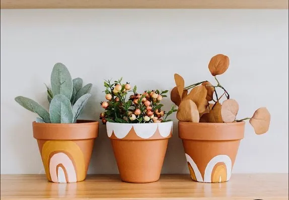 A trio of terracotta planters, each hand-painted with a unique boho rainbow and scallop design. They are perfect for housing small succulents or herbs and brightening up a windowsill.