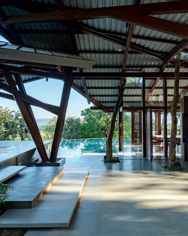 The Lateral Verandah House finds its footing on a sloping hill in Lonavala, its unique timber frame creating a dialogue with the landscape. We used raw basalt walls to ground the structure, a nod to the region's architectural history, creating a space that feels both of the earth and elegantly light.