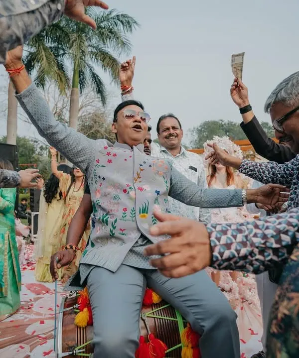 The groom's father sitting on a dhol, surrounded by dancing family members. We love it when the whole family gets into the spirit of the baraat!