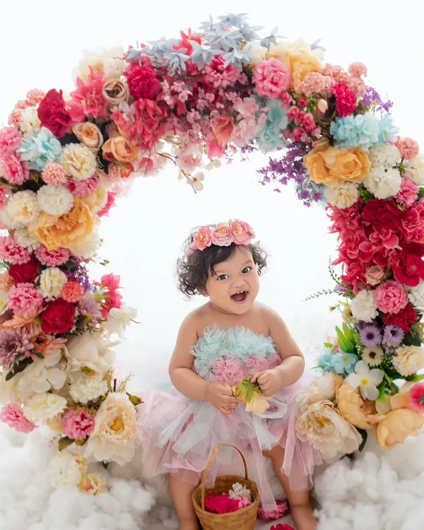 A flower among flowers. This baby girl's joyful laugh is infectious as she sits within a vibrant floral wreath.