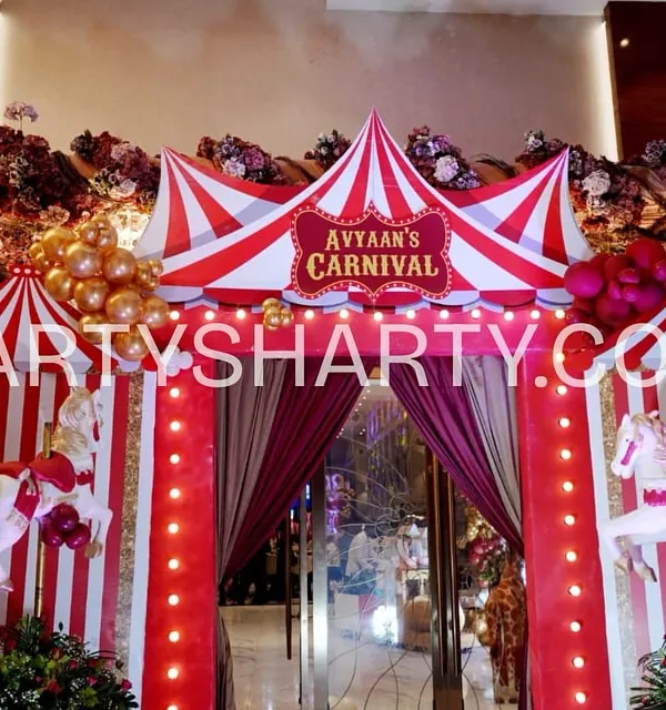 A spectacular carnival tent entrance, featuring red and white stripes, carousel horses, and a personalized sign, welcoming guests to the main event.