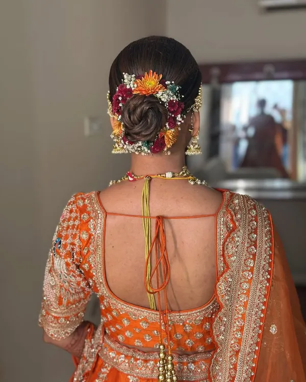 A beautiful bridal bun for Saloni. I wove fresh, colorful flowers into her updo to create a vibrant and traditional look that perfectly matched her orange lehenga.