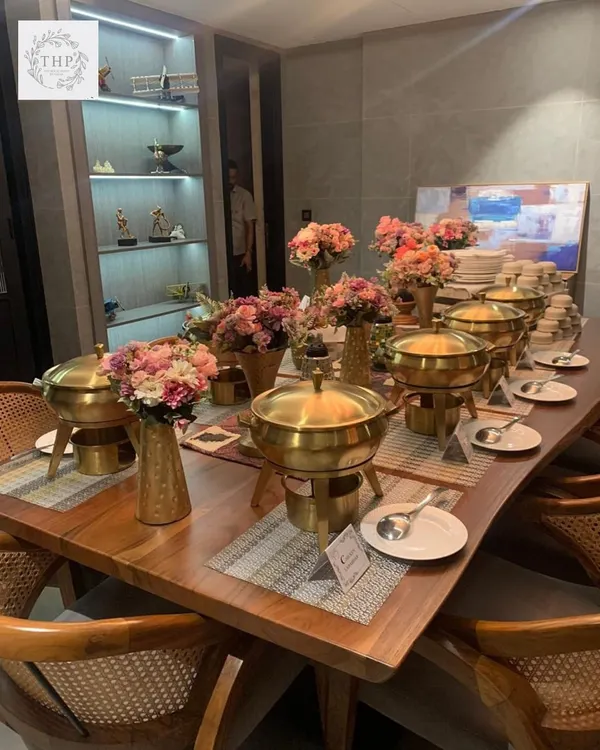 Your dining table, transformed. We don't just bring food; we bring an entire aesthetic with our elegant brass serving dishes, floral arrangements, and professional setup to create a luxury dining experience.