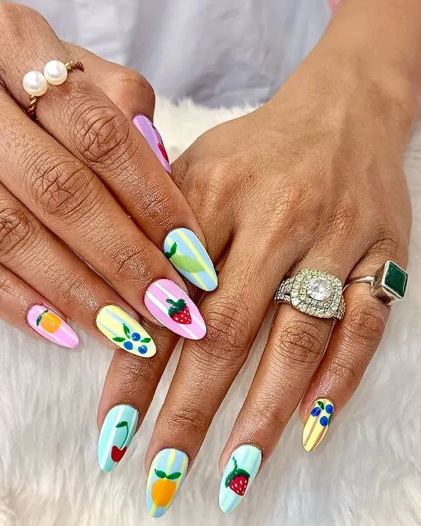A fruity fiesta for your fingertips. This fun and colorful set features a mix of pastel-striped nails, each adorned with a different hand-painted fruit like strawberries, cherries, and oranges.