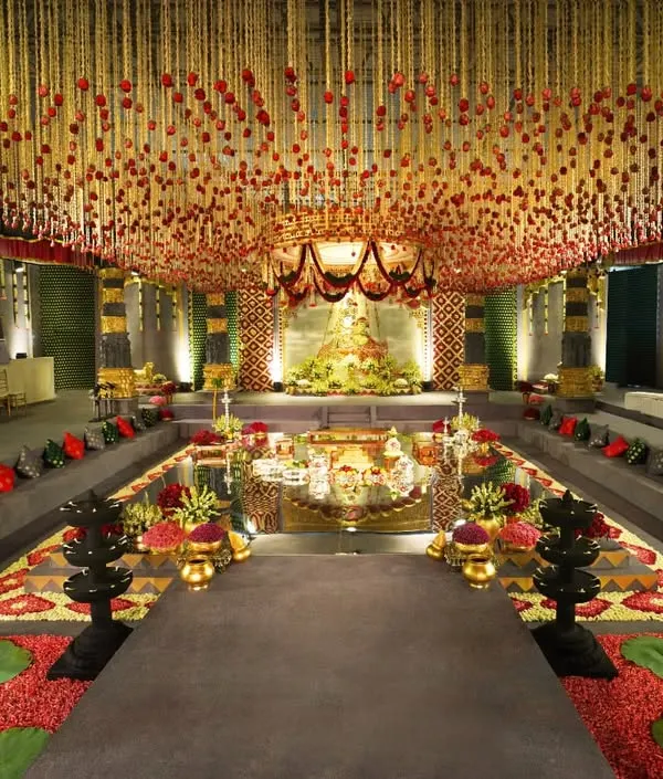 We transformed a hotel ballroom into a breathtaking temple sanctuary. This wide view showcases the grand scale of our design, featuring a central water body, towering custom-built pillars, and a ceiling adorned with thousands of floral strings, creating a truly immersive and sacred space for the wedding ceremony.