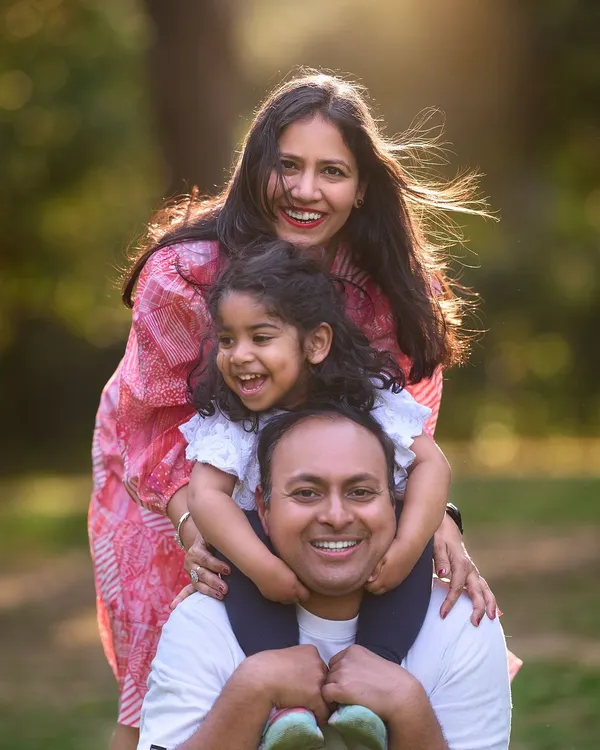 A beautiful family portrait where everyone's personality shines through. The layered pose with their daughter on her father's shoulders creates a lovely sense of closeness and joy.