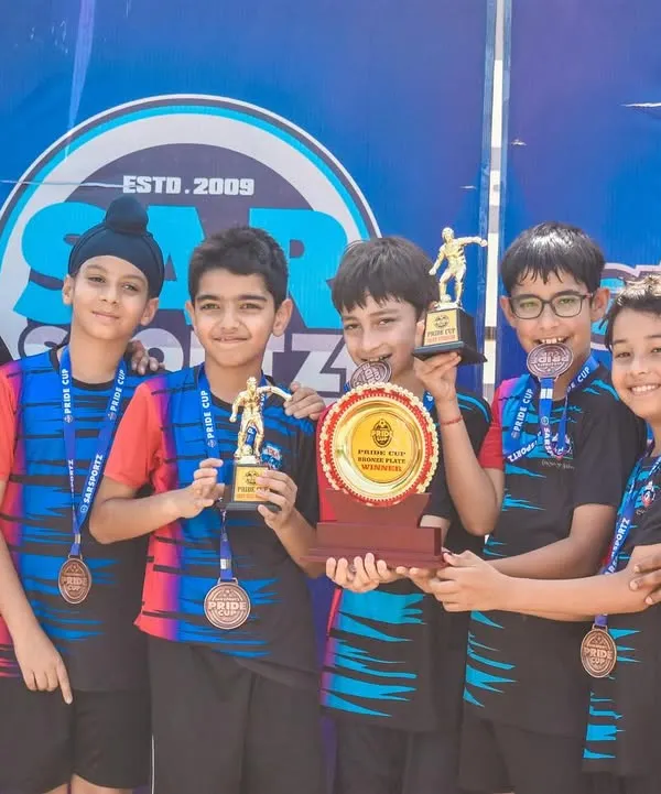 A team of young champions celebrates with their medals and trophy after winning their division in the Pride Cup.