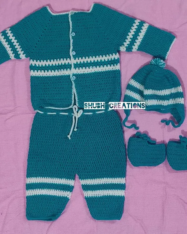 This complete hand-crocheted baby set, featuring a striped sweater, matching pants, a pom-pom hat, and tiny booties, is made with the softest yarn for your little one's comfort.