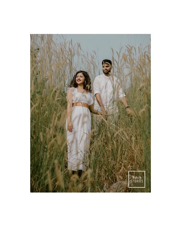 A serene portrait of a couple standing together in a field of tall grass. The natural, earthy tones and their calm connection create a beautifully rustic engagement photo.
