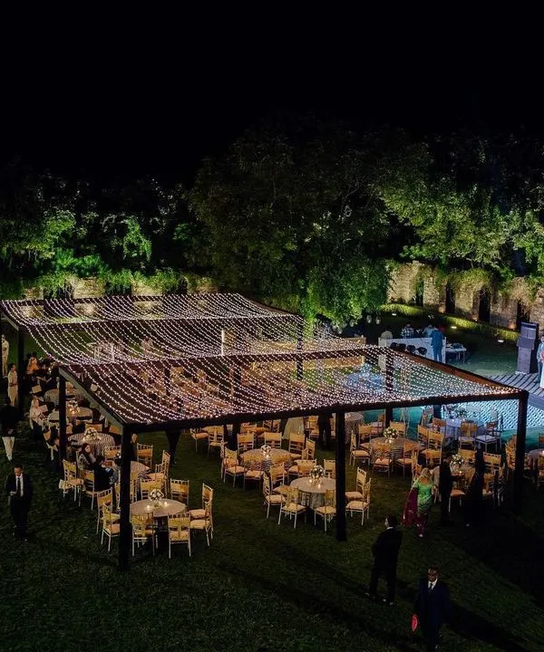 A breathtaking wide-angle view of an outdoor reception at Alila Fort. The guest seating is arranged under a massive canopy of fairy lights, creating a starlit sky effect for a truly magical evening.