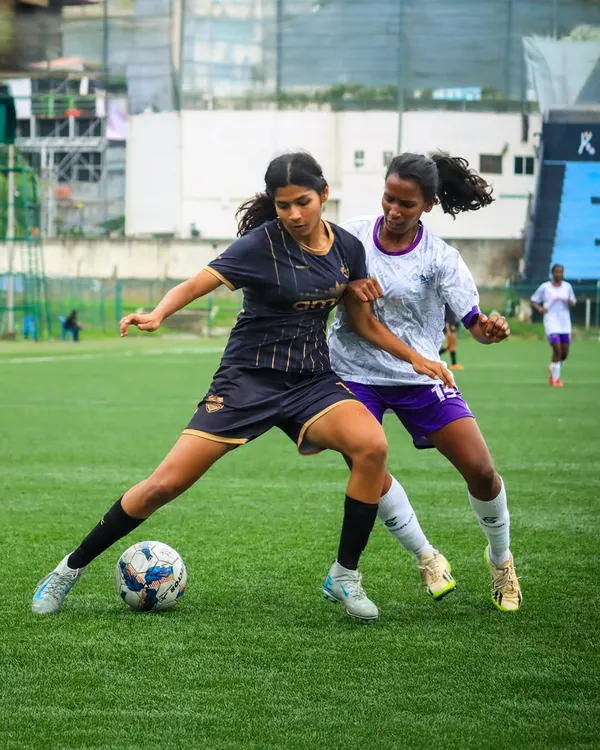 A girls' school football match in full swing, with a player skillfully shielding the ball from a defender during a competitive game.