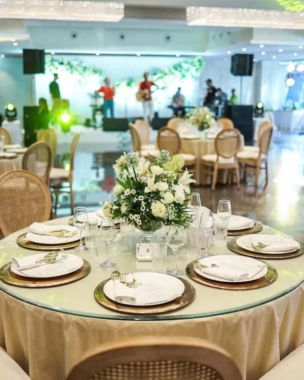 An elegant round table set for a celebration, with a live band performing in the background. We create an ambiance where fine dining and entertainment come together seamlessly.