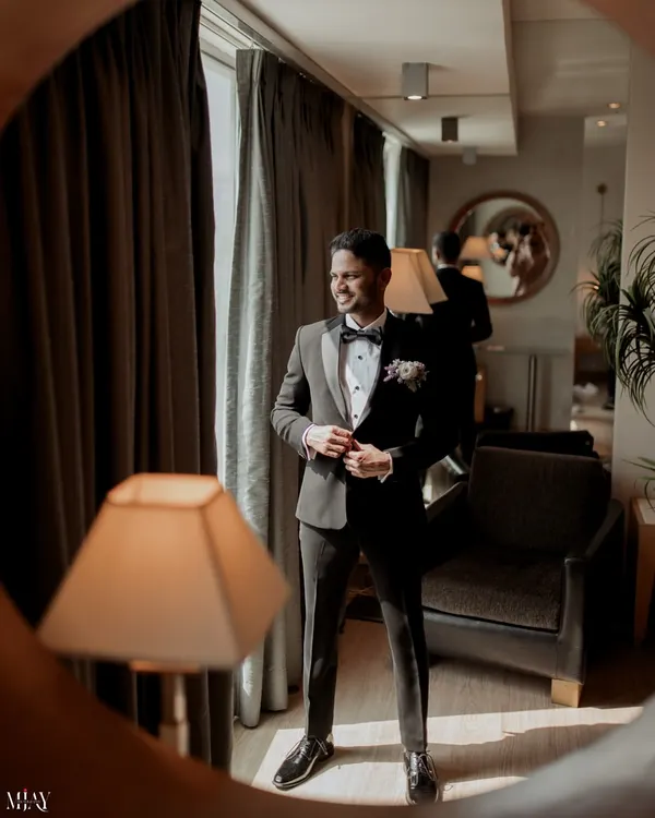 A stylish portrait of the groom in his classic black tuxedo, captured through a mirror for a creative effect.