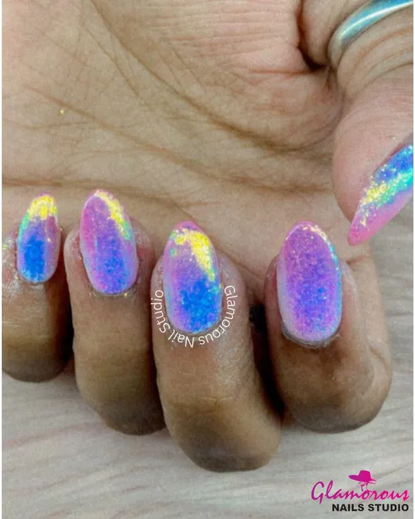 A galaxy of color on your nails. This vibrant, shimmering look is created with a mix of yellow, blue, and pink glitter polish for a multi-tonal, iridescent effect.