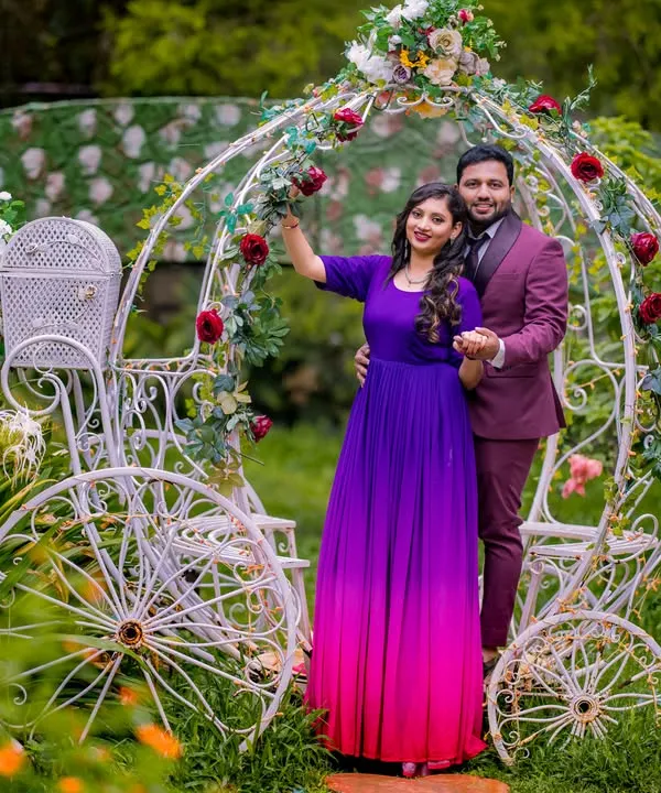 A classic fairy tale moment. This couple shares a dance in front of a whimsical white carriage, decorated with red roses. The bride-to-be's ombre gown adds a beautiful splash of color to the scene.