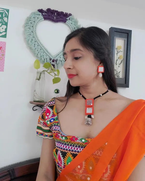 Here I am wearing one of my custom Navratri necklace sets. I designed this vibrant orange fabric jewelry to match my traditional chaniya choli, featuring mirror work and a statement pendant.