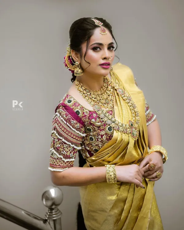 This is the quintessential South Indian bridal look I specialize in. The set features intricate temple jewelry with a matte gold finish, including a detailed choker, a longer kasina sara (coin necklace), matching jhumkas, and a maang tikka, all coordinated to create a regal and timeless appearance for the main wedding ceremony.