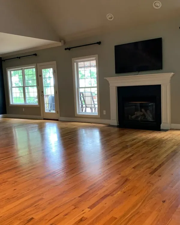 This spacious living room features a glossy, medium-toned hardwood floor that I installed to bring a sense of warmth and tradition. The polished finish reflects light beautifully, making the entire space feel grand and inviting.
